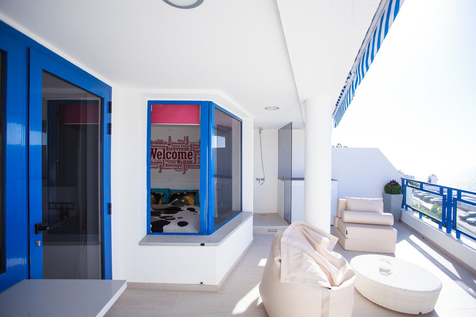 Ein Balkon mit weißen Möbeln und einer blauen Tür