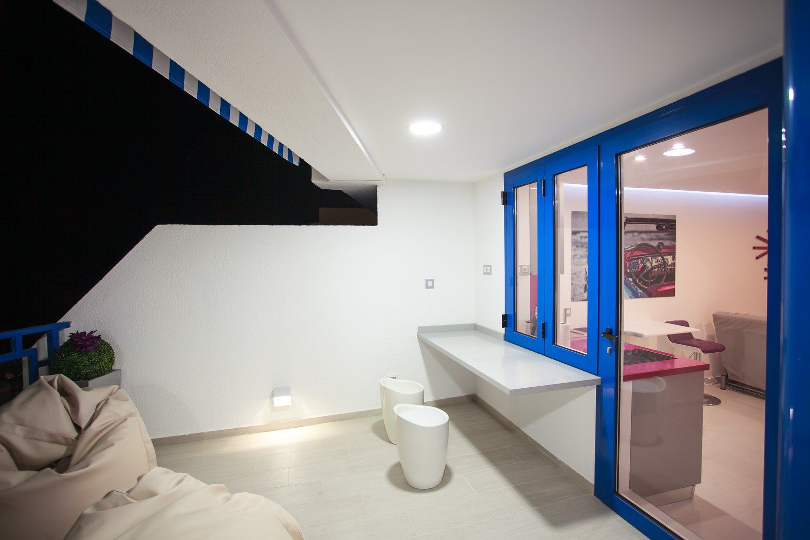 Ein Balkon mit blauen Glasschiebetüren, die zu einem Wohnzimmer führen.
