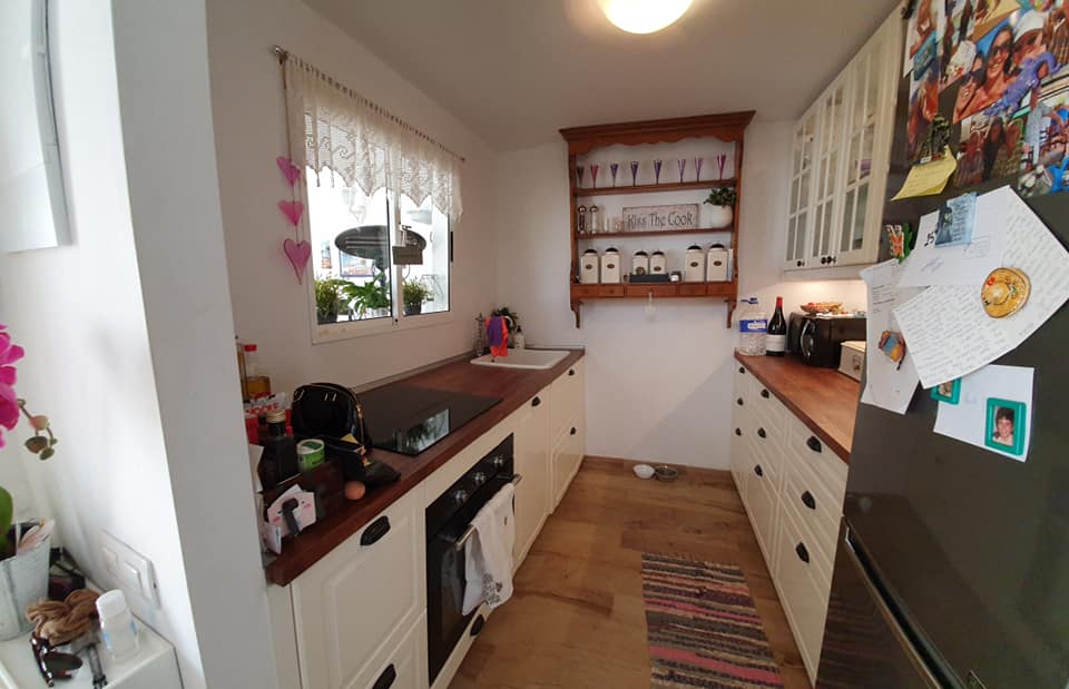 Eine Küche mit weißen Schränken, einem Herd, einem Kühlschrank und einem Fenster.