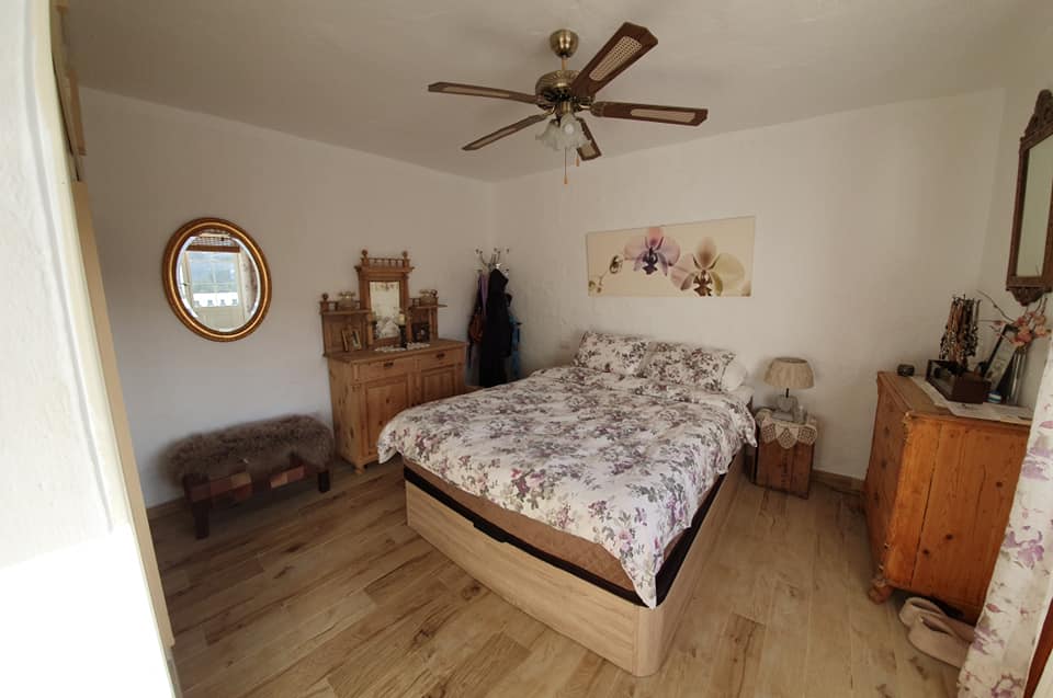 Ein Schlafzimmer mit Bett, Kommode, Spiegel und Deckenventilator.
