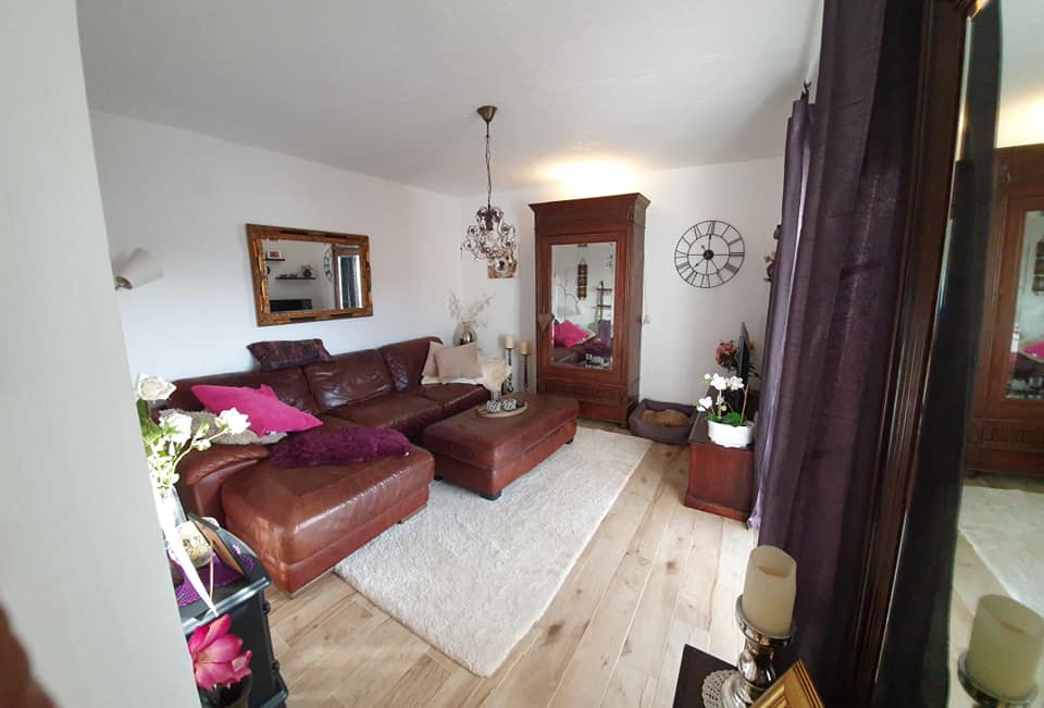 Ein Wohnzimmer mit einer braunen Couch und einer Uhr an der Wand
