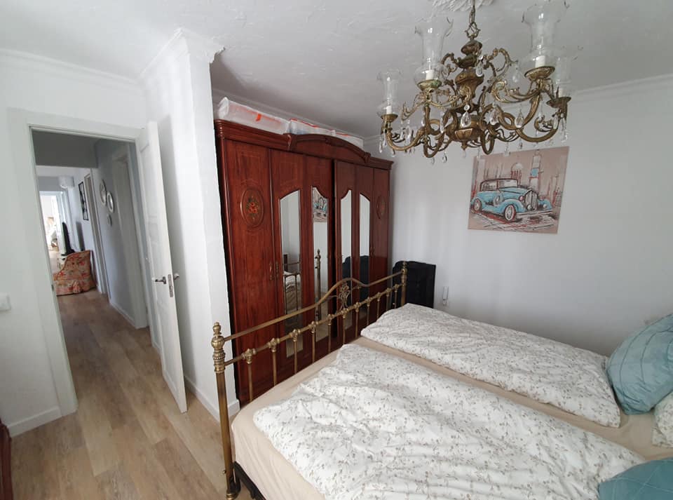 Ein Schlafzimmer mit zwei Betten, einem Kronleuchter und einem Gemälde an der Wand.