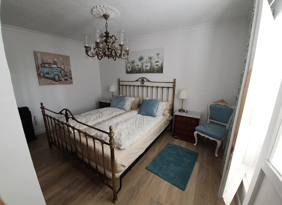 Ein Schlafzimmer mit zwei Betten, zwei Nachttischen, einem Stuhl und einem Kronleuchter.