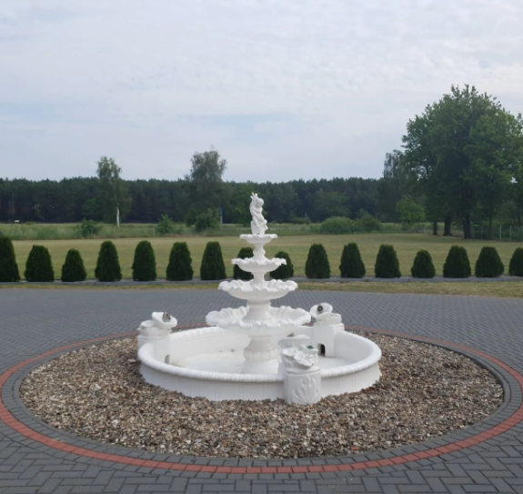 Ein weißer Brunnen steht in der Mitte einer gepflasterten Auffahrt