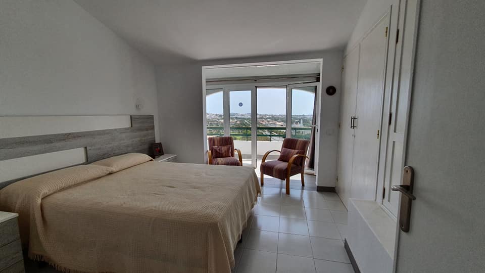 Ein Schlafzimmer mit großem Bett, Stühlen und Balkon.