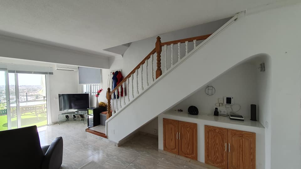 Ein Wohnzimmer mit Treppe, die in den zweiten Stock führt.