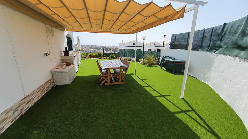 Eine Terrasse mit Tisch und Stühlen unter einem Baldachin