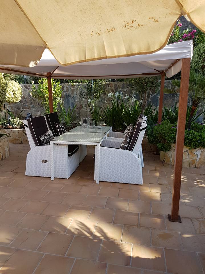 Eine Terrasse mit Tisch und Stühlen unter einem Sonnenschirm