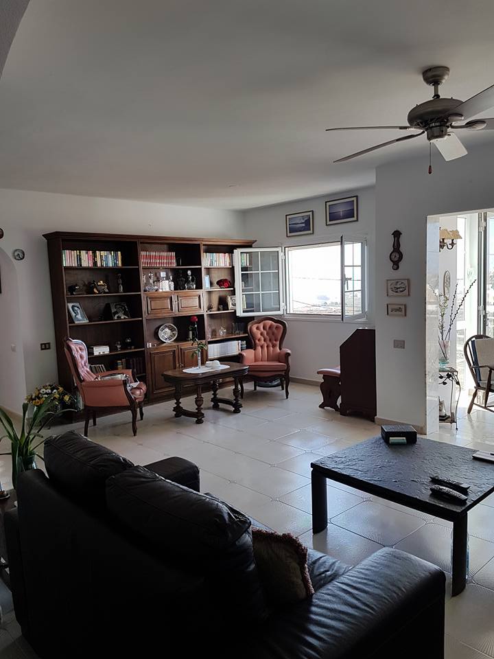 Ein Wohnzimmer mit Couch, Tisch, Stühlen und Deckenventilator.