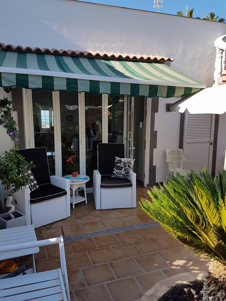 Eine Terrasse mit grün-weißer Markise und Stühlen