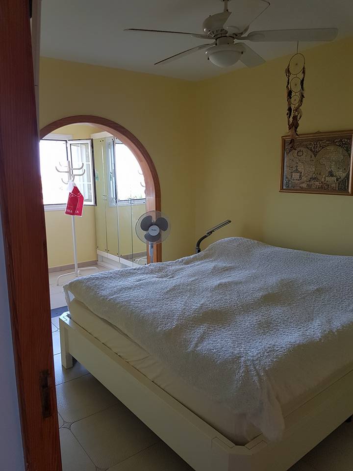Ein Schlafzimmer mit einem Bett und einem Deckenventilator