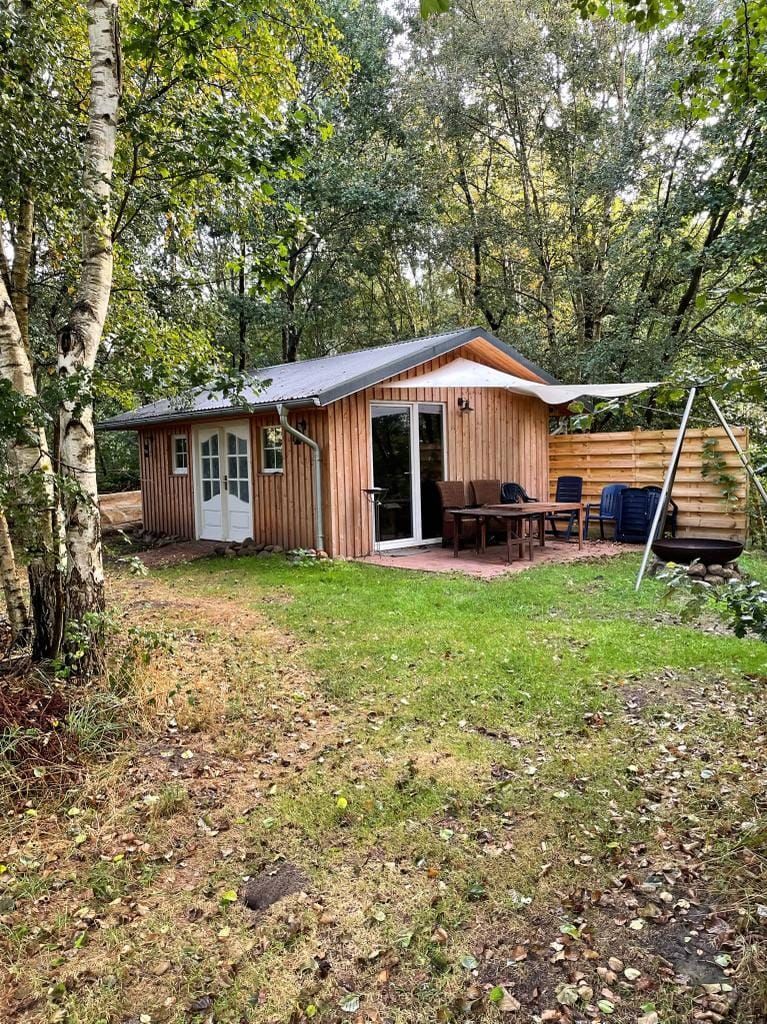 Ein kleines Holzhaus mit Terrasse mitten im Wald.