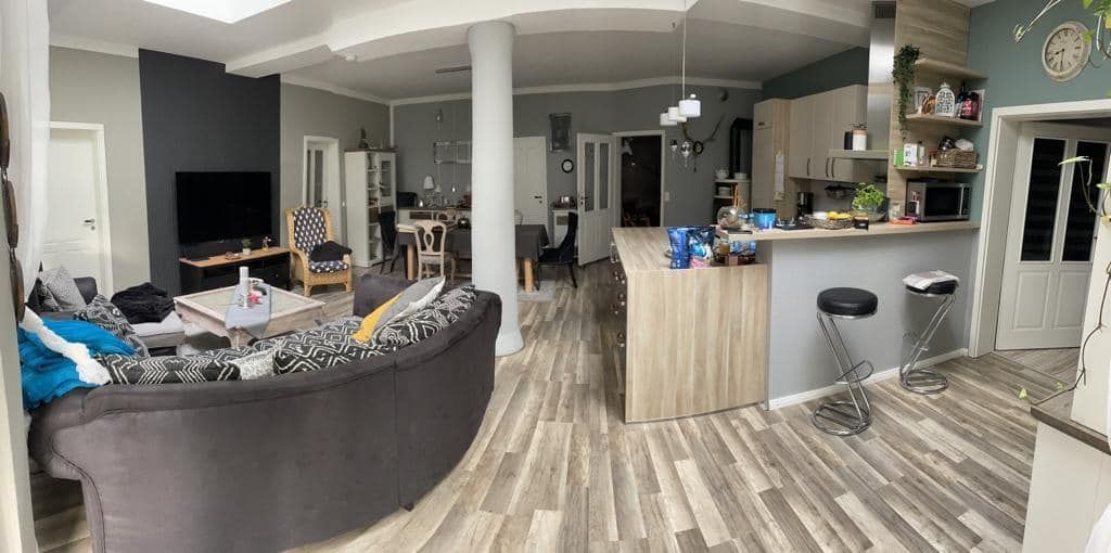 Ein Wohnzimmer mit einer großen Couch und einer Küche im Hintergrund.