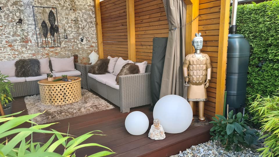 Eine Terrasse mit einer Couch, einem Tisch, Bällen und einer Männerstatue.