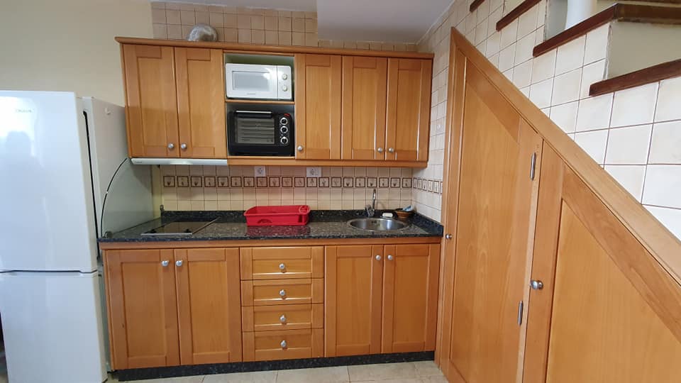 Eine Küche mit Holzschränken, Kühlschrank, Mikrowelle und Spüle.