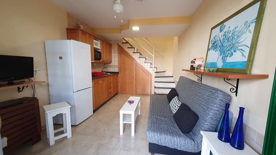 Ein Wohnzimmer mit Couch, Kühlschrank, Fernseher und Treppe.