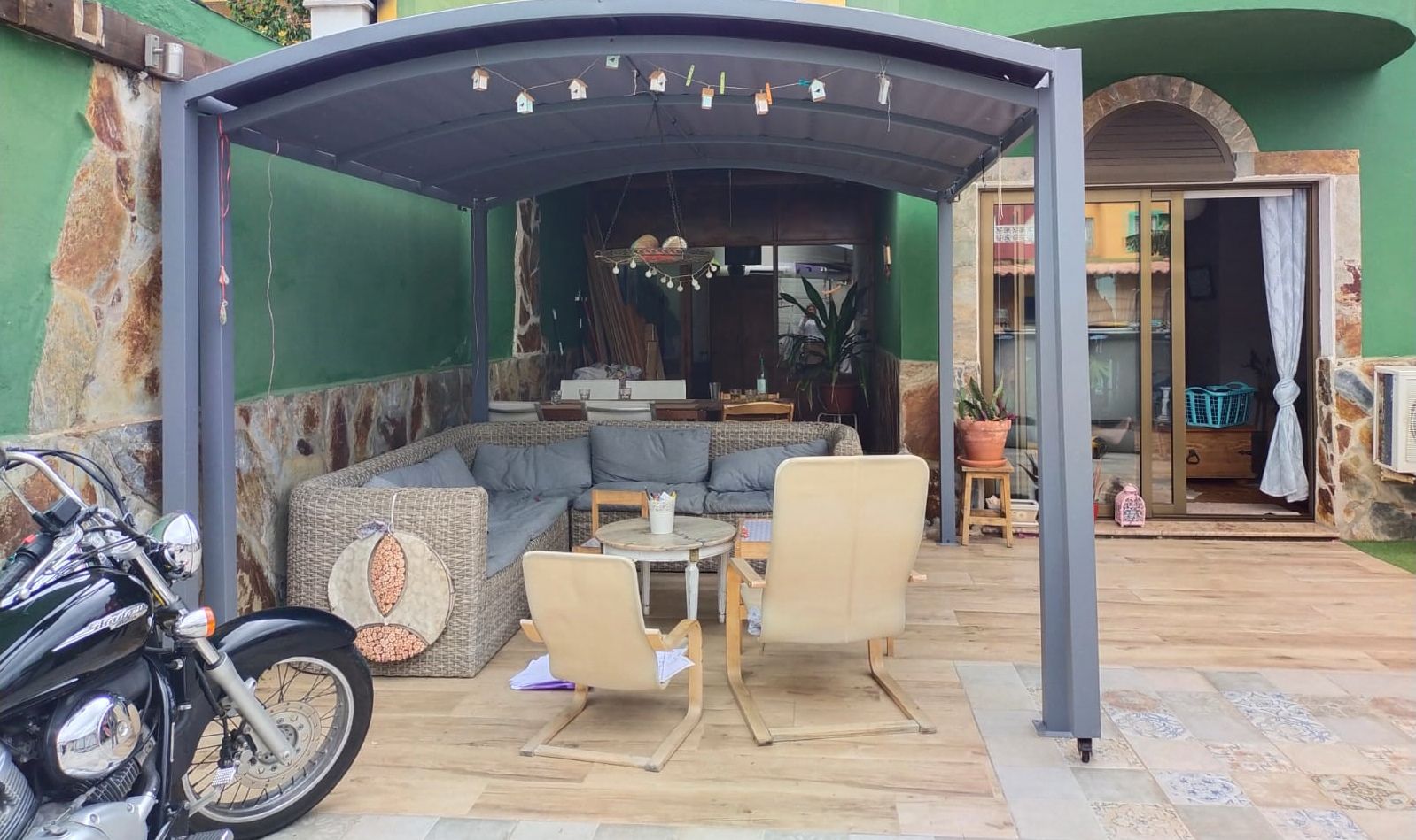Vor einer überdachten Terrasse ist ein Motorrad geparkt.