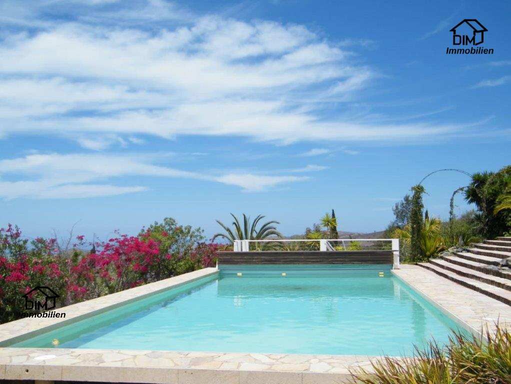Ein großer Swimmingpool, umgeben von Blumen und Treppen an einem sonnigen Tag.