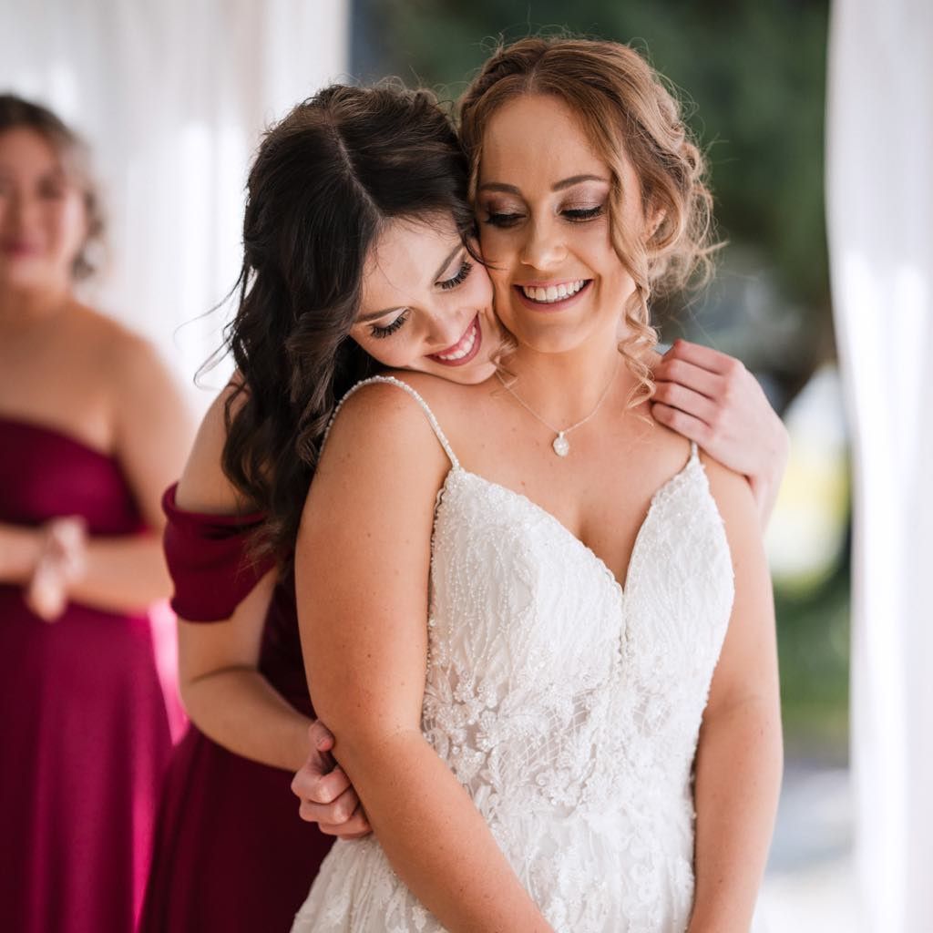 A Woman in a White Dress is being hugged — Xquisite Styles in Mount Warrigal, NSW
