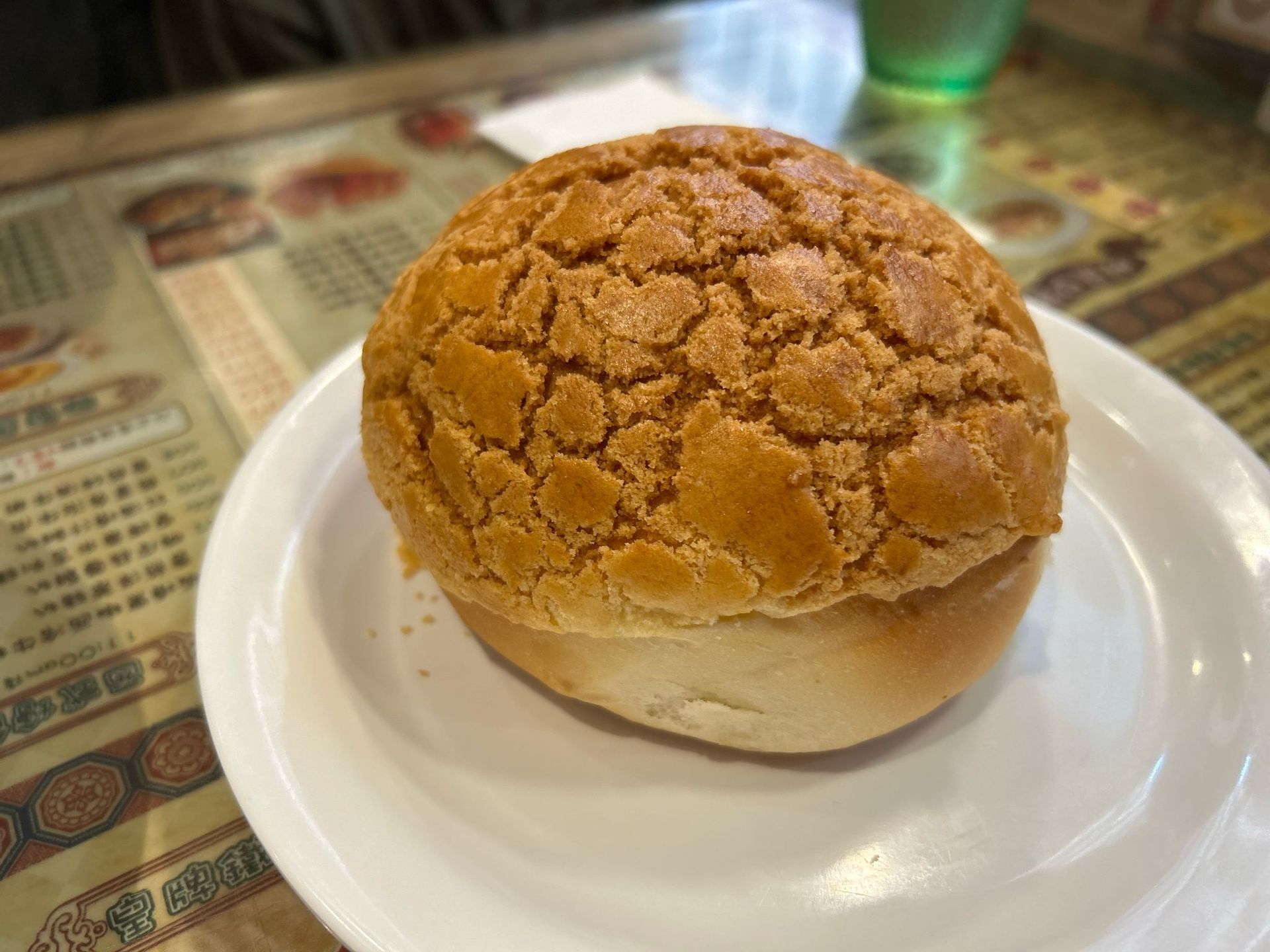 Round bread roll with a cracked golden crust on a white plate