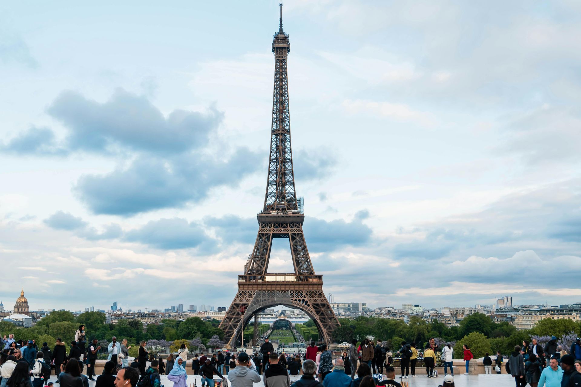 Eiffel Tower rising above a crowd in Paris under a cloudy sky