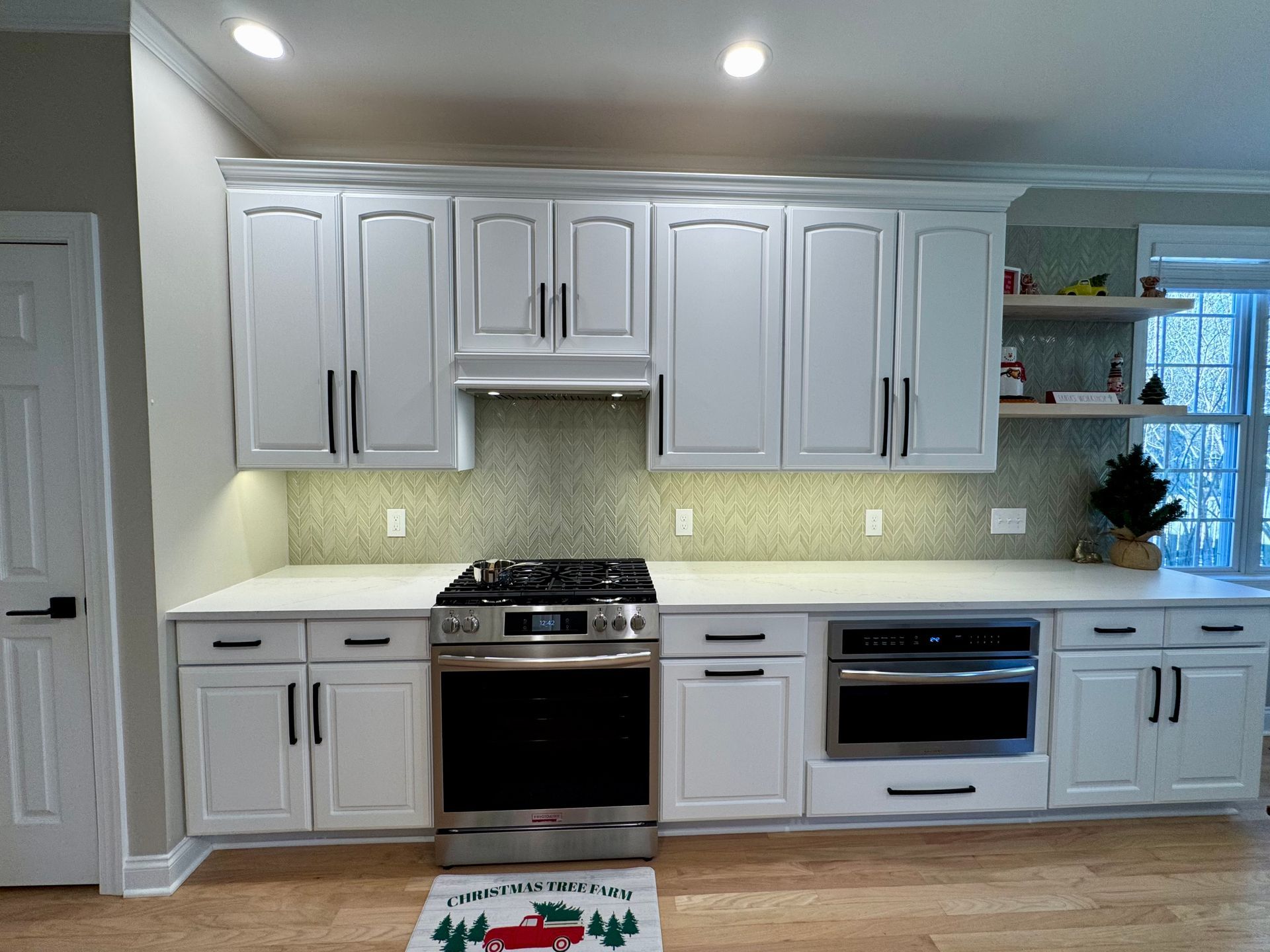 Bright white modern kitchen with built-in oven, cooktop, and under-cabinet lighting