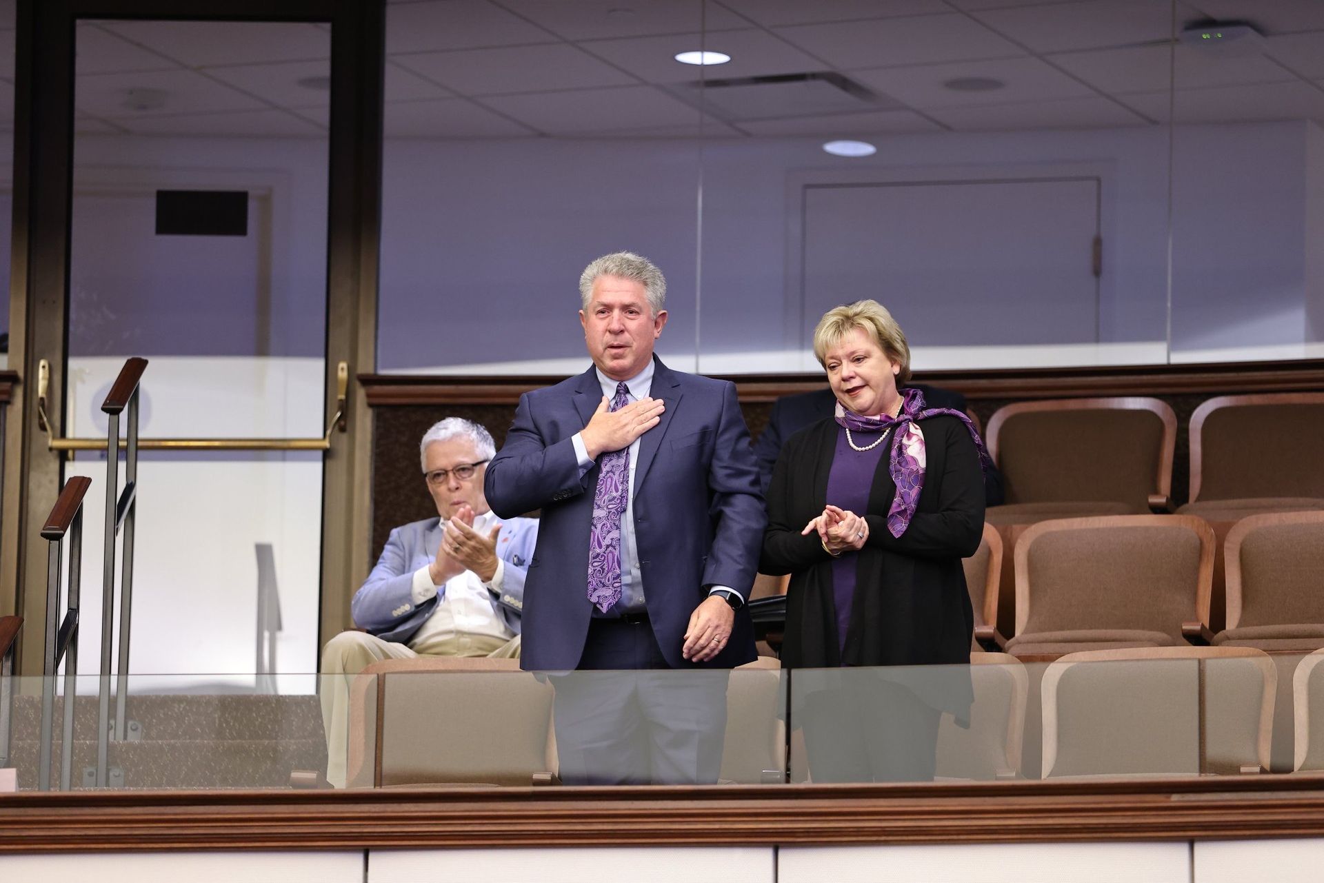 A man in a suit and tie is standing next to a woman in a purple scarf.