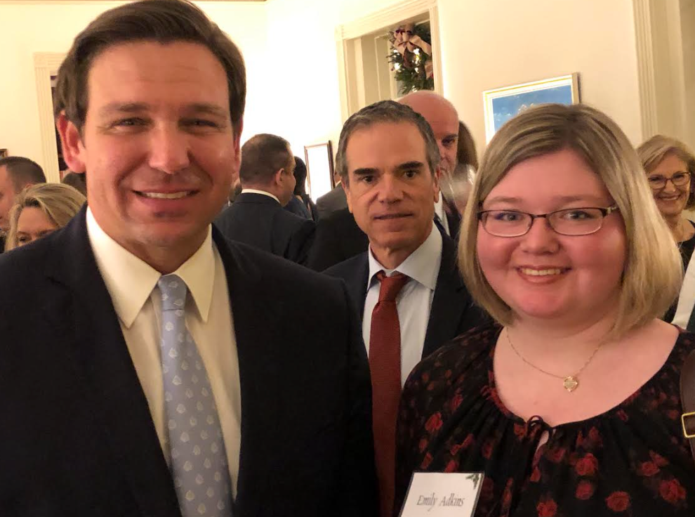 A man in a suit and tie is standing next to a woman with glasses.