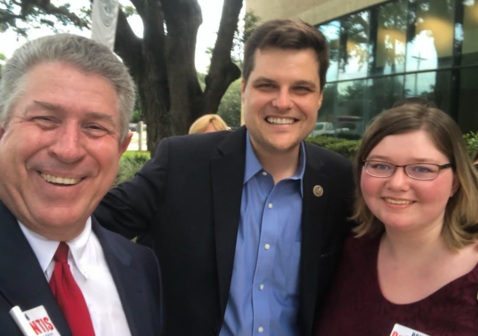 A man in a suit and tie poses for a picture with two other people