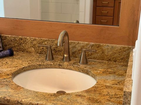A bathroom vanity featuring a gold-flecked granite countertop, a white oval sink, and a brushed-nickel faucet.
