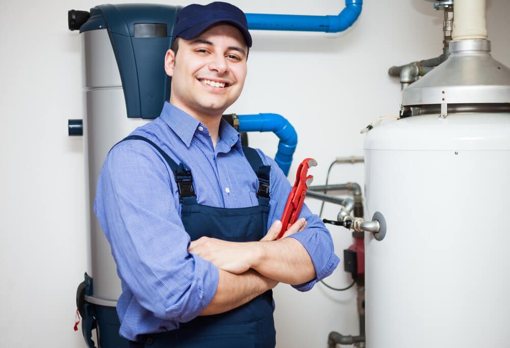 Plumber Holding a Wrench in Front of A Water Heater — Professional Plumber in Toowoomba