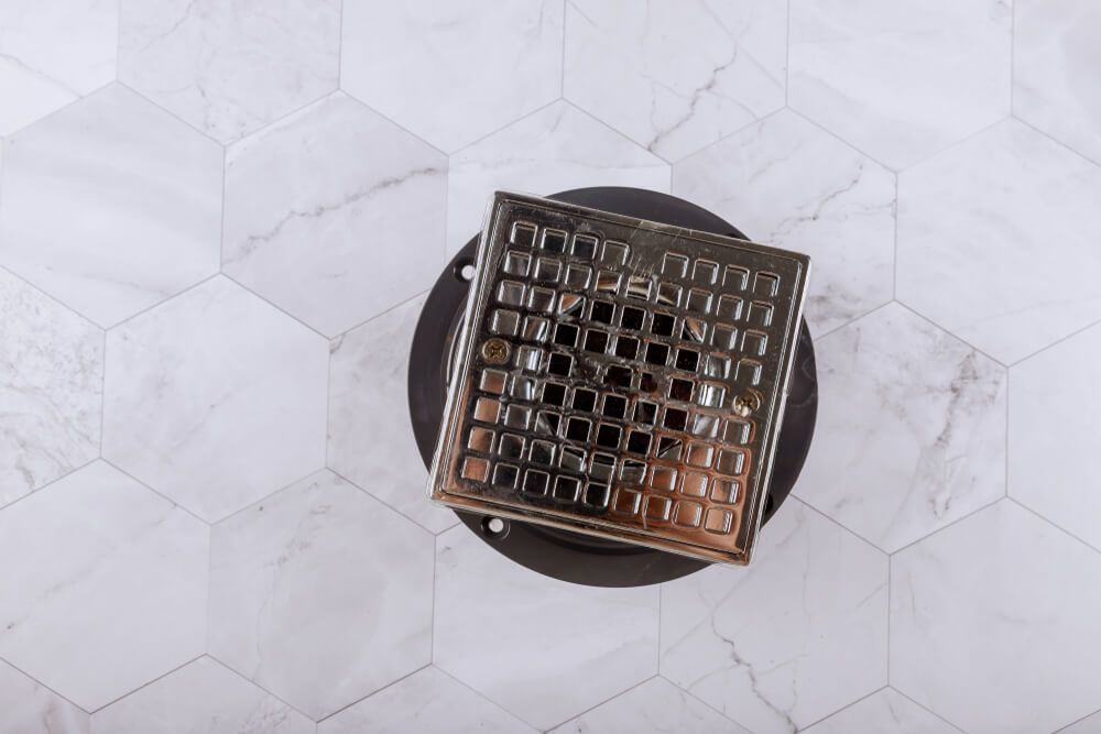 Drain Is Sitting on Top of A White Tile Floor — Professional Plumber in Toowoomba 