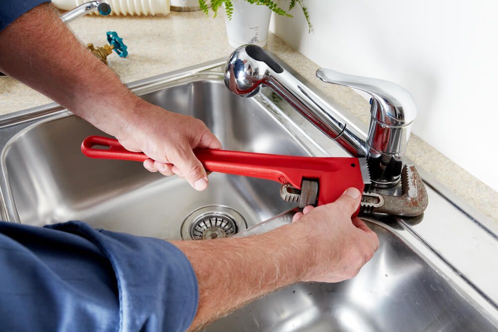 Plumber Fixing a Sink with A Red Wrench — Professional Plumber in Toowoomba 