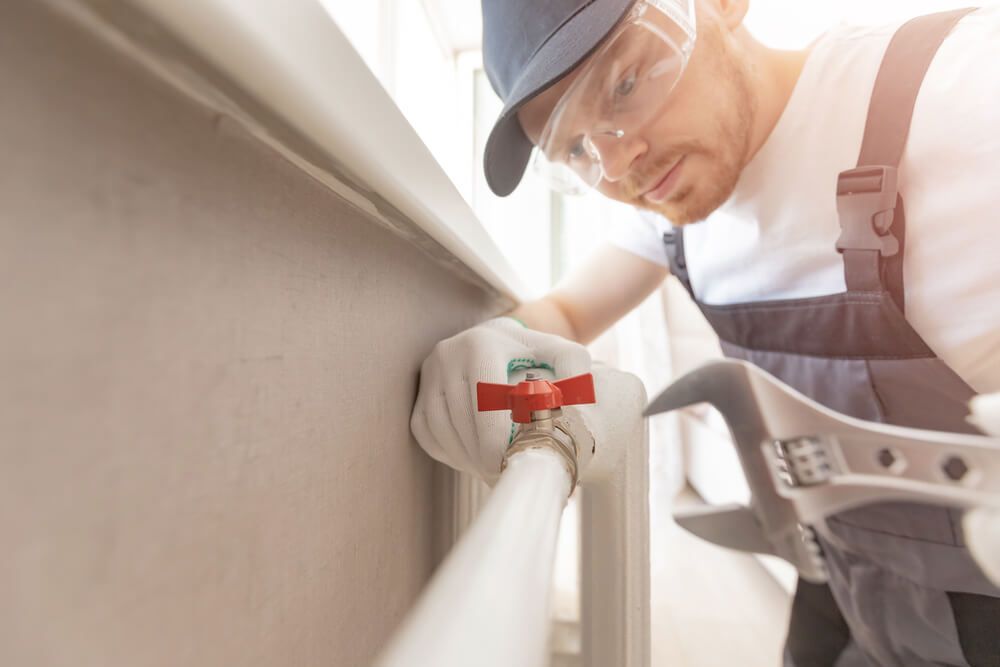 Man Fixing a Radiator Having a Red Knob with A Wrench — Professional Plumber in Toowoomba 