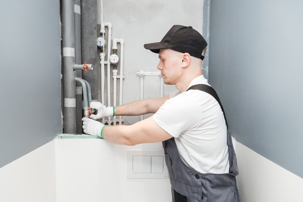 Man Fixing a Pipe in A Bathroom with A Wrench — Professional Plumber in Toowoomba