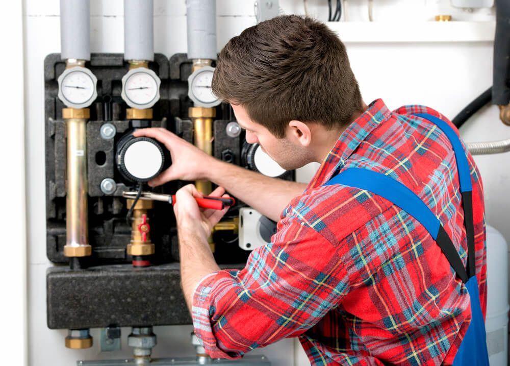 Man Working on A Boiler Having Three Dials — Professional Plumber in Toowoomba 