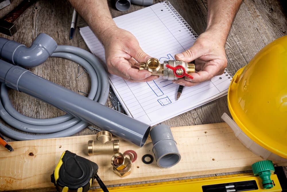 Plumber Working on A Pipe and Holding a Valve — Professional Plumber in Toowoomba