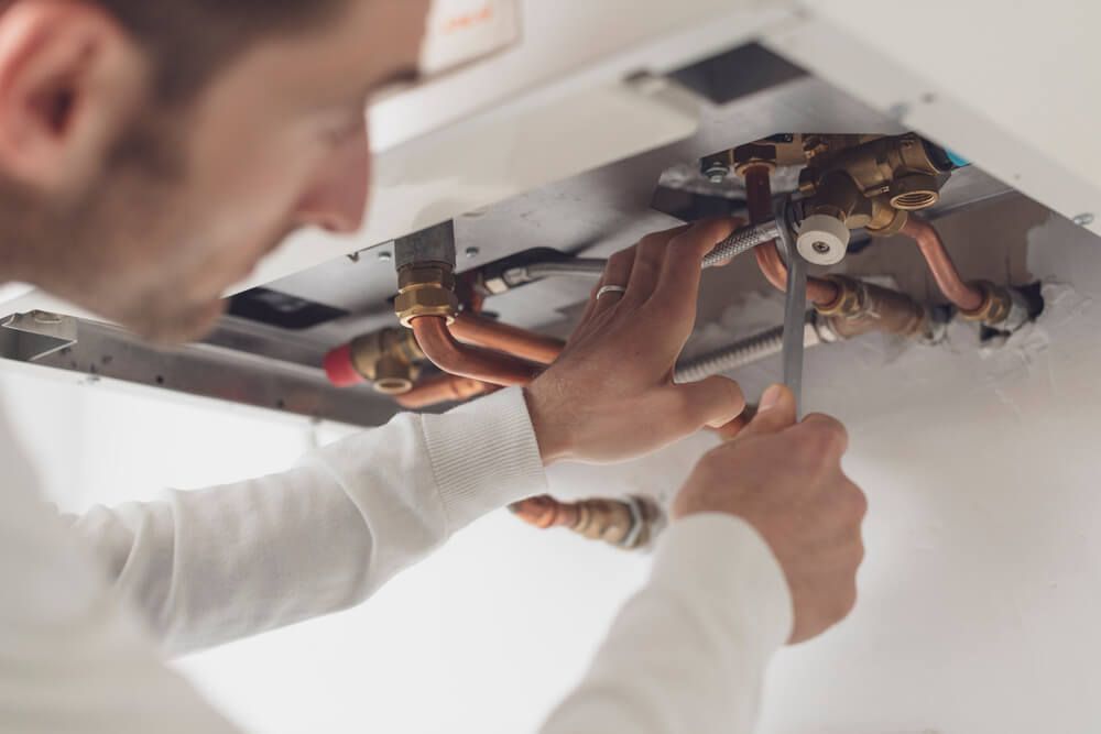 Man Fixing a Water Heater with A Wrench — Professional Plumber in Toowoomba 