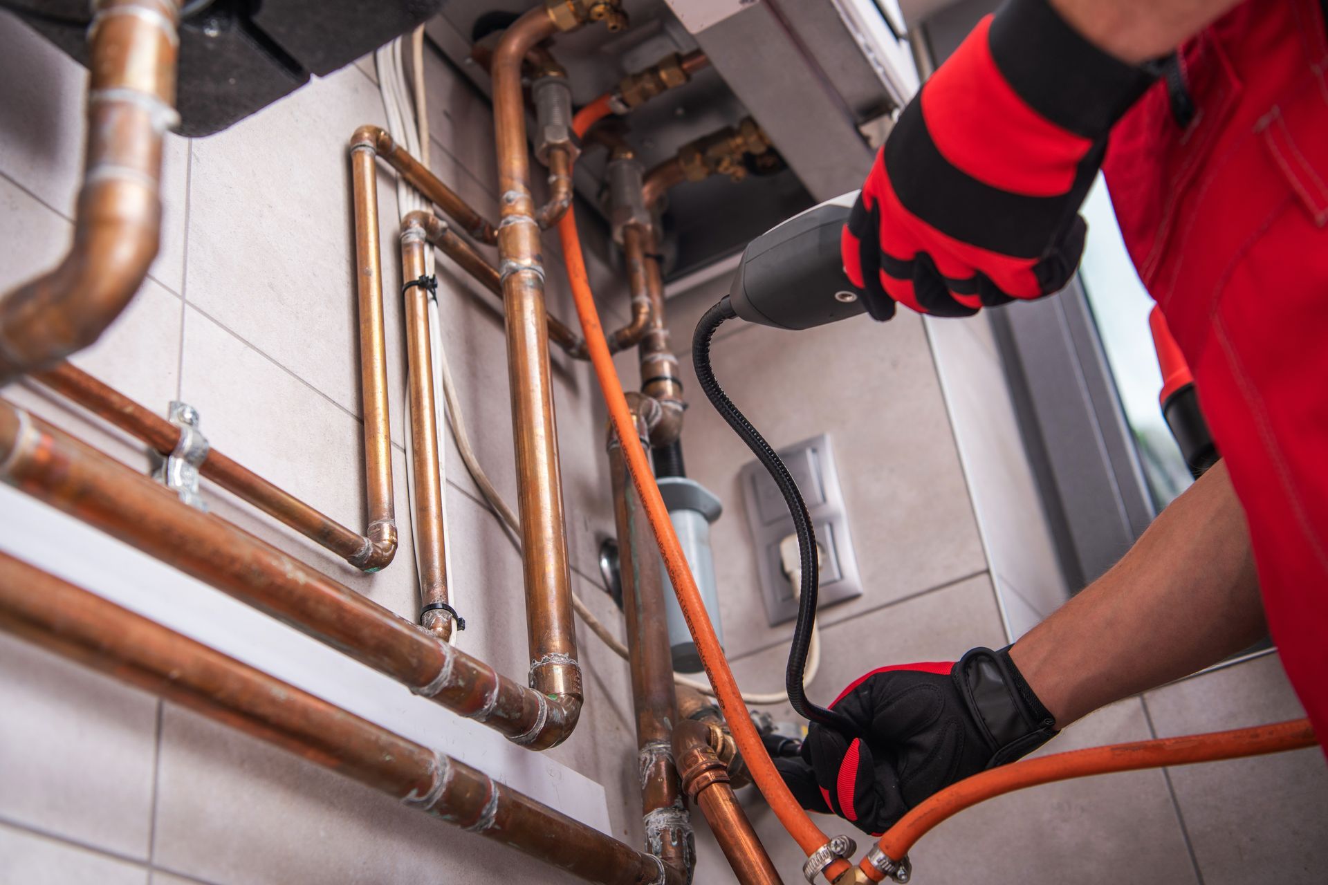 A Person in Red Coveralls Working on Copper Pipes — Professional Plumber in Toowoomba
