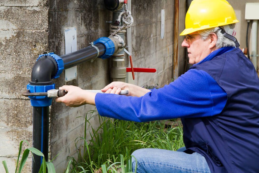 Man Wearing a Yellow Hard Hat Working on A Pipe — Professional Plumber in Toowoomba