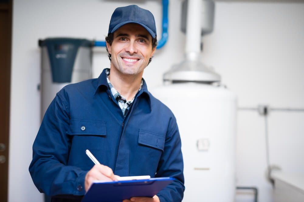 Man in A Blue Uniform Is Holding a Clipboard and Smiling — Professional Plumber in Toowoomba