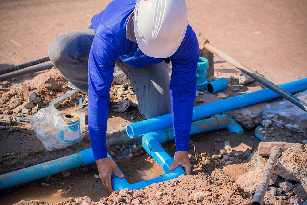 Man Working on A Pipe in The Dirt — Professional Plumber in Toowoomba