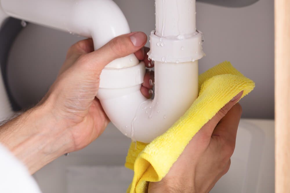 Someone Cleaning a Sink Pipe with A Yellow Cloth — Professional Plumber in Toowoomba