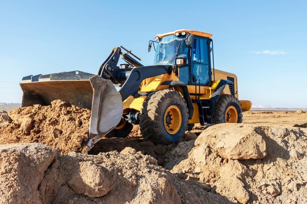 Excavator moving sand in its bucket during a landscaping excavation project — Stan Davies Excavations in Newcastle, NSW
