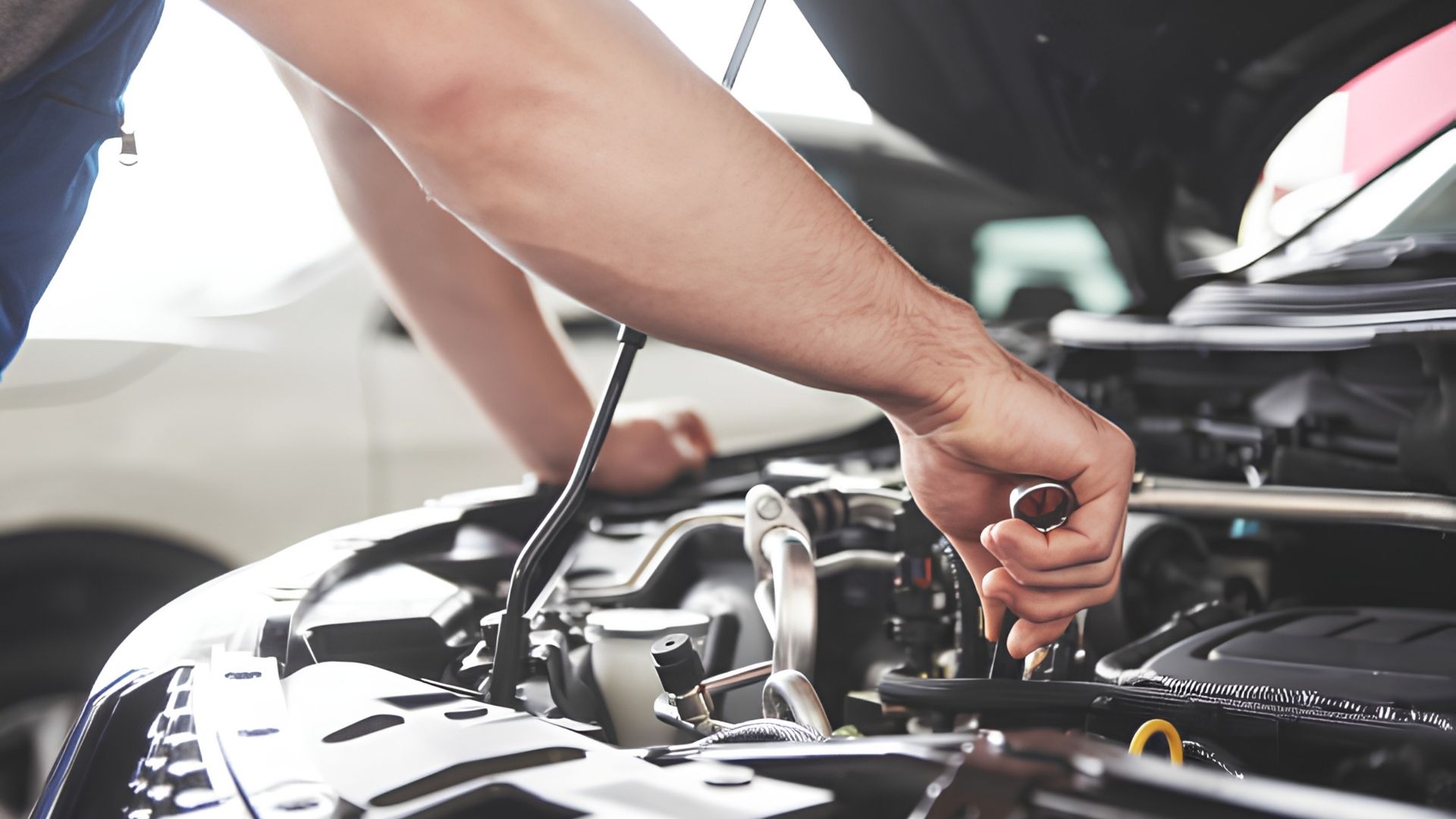 Mechanic tightening a bolt in a car engine bay with a wrench