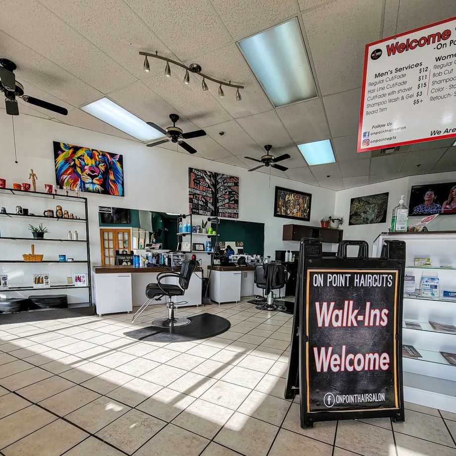 Hair salon interior with styling chairs, shelves, wall art, and a “Walk-Ins Welcome” sign.