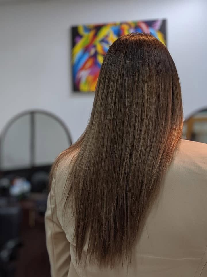Person with long brown hair seen from behind in a room with colorful wall art and a mirror.