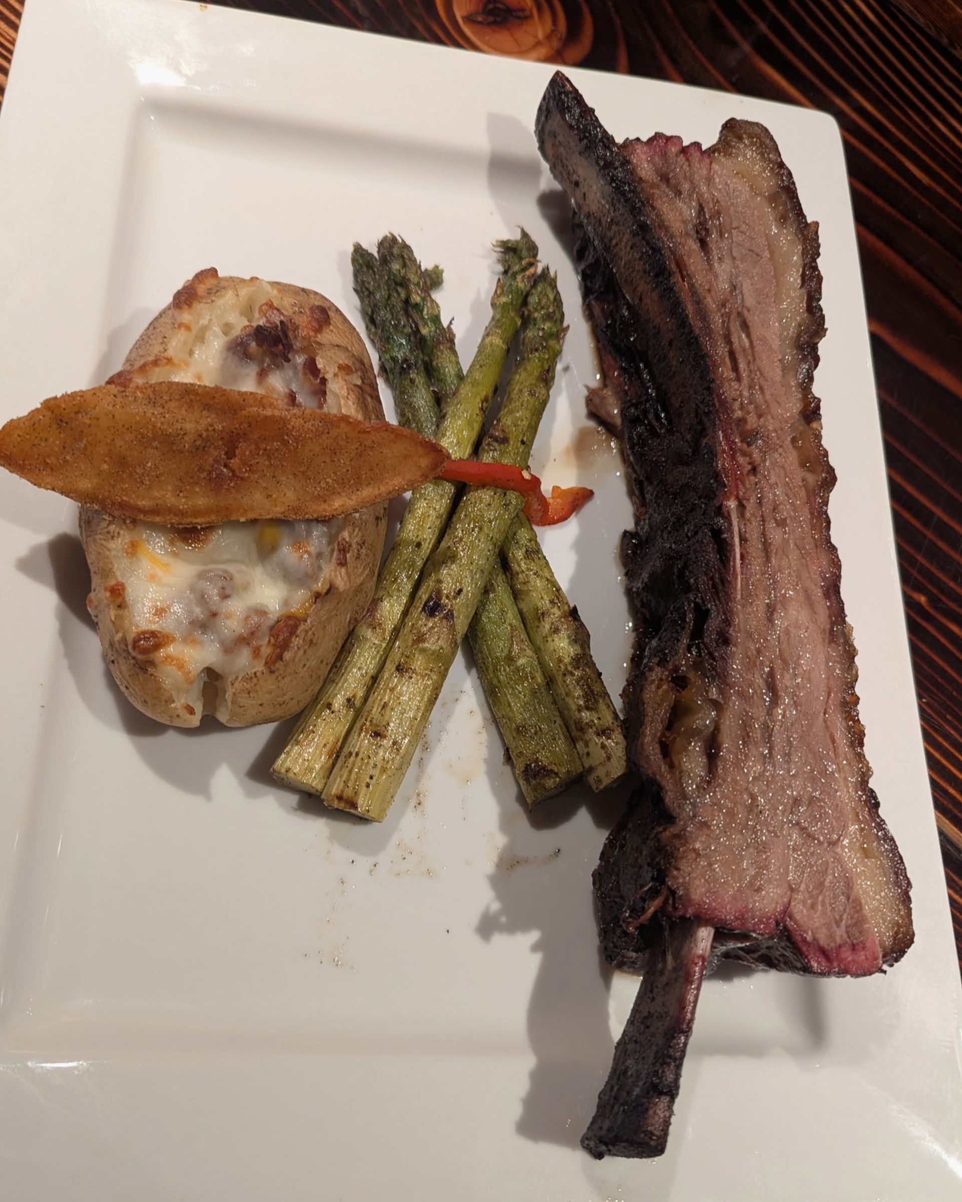 Plated steak with grilled asparagus and a potato on a white plate