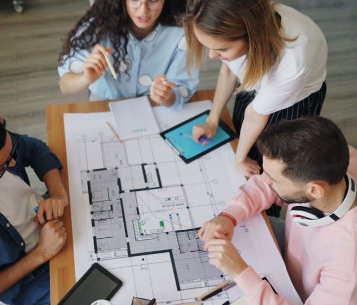 A group of people are sitting around a table looking at a floor plan.