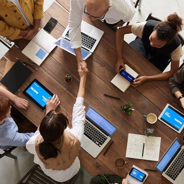 A group of people are sitting around a table shaking hands